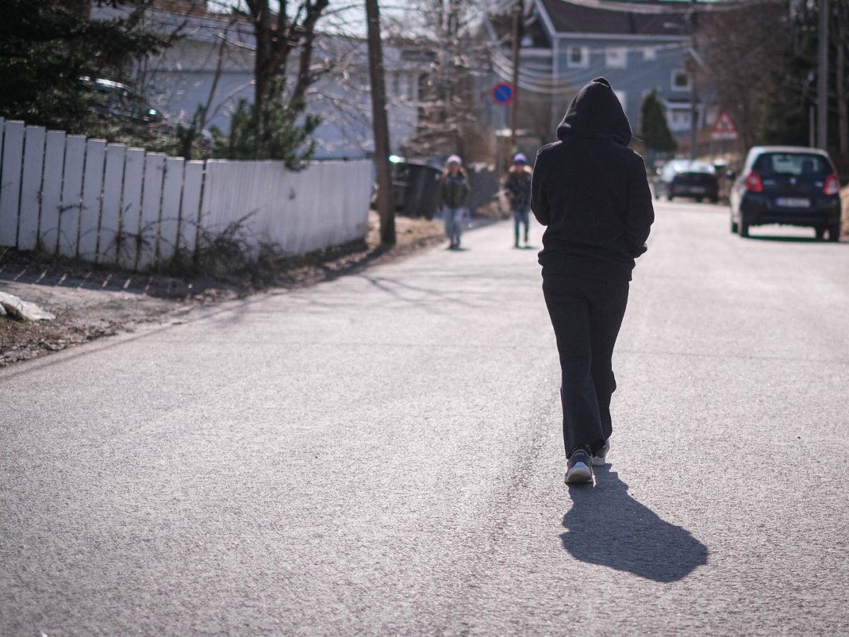 En anonym person går langs en vei. Bilde